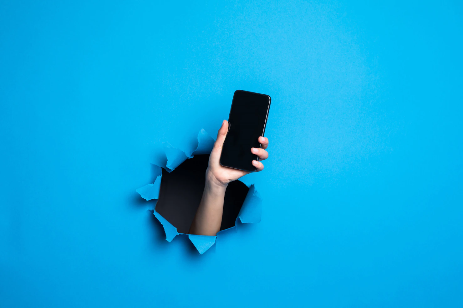 close up woman hand holding phone with screan adv through blue hole paper wall 231208 1689 Telefon Kullanım Alışkanlığı 2023
